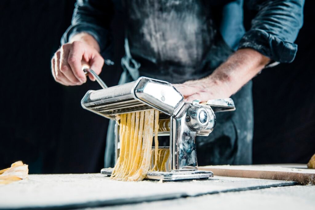 Hobby chef making fresh tagliatelle with pasta machine